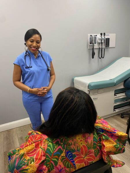 Certified Nurse Practitioner Carol Williams warmly smiling while professionally explaining Grateful Healthcare’s services to a seated client.